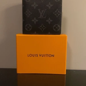 Lv Plånbok  - Säljer en svart grå Lv plånbok. Helt oanvänd, ser precis ny ut. Kan hålla upp till 8 st samtidigt plus två fickor som man kan lägga sedlar i. Ny pris runt 5000 kr, Pris 2399, vid snabb affär kan sänka. Kom privat om du vill flera bilder eller undrar något.