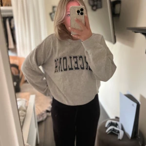 Grå sweatshirt med Barcelona-tryck - Säljer en grå sweatshirt med texten 'Barcelona' i mörkblått på bröstet. Tröjan har långa ärmar och ribbade muddar vid ärmslut och nederkant💗