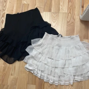 Två volangkjolar svart & vit - Säljer två korta kjolar med volanger, en i svart och en i vit. Båda för 30kr!!! Ena är från Gina och andra kapphal kids!