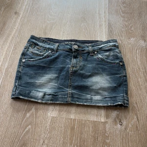 Jeanskjol från Fashion Play, M (barnstorlek) - Snygg kort jeanskjol från Fashion Play i tvättad blå denim med slitna detaljer och rå kant nertill. Klassisk femficksmodell med synliga sömmar!💕