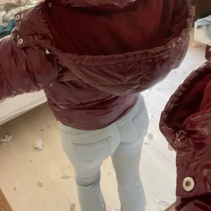 Vinröd pufferjacka med huva från Nelly - Säljer en vinröd pufferjacka med glansig finish och stor huva från Nelly . Jackan har dragkedja framtill, långa ärmar och en oversized look. Perfekt för kalla dagar och riktigt snygg till jeans. 