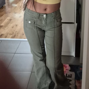 Gröna bootcut jeans från HM - Snygga olivgröna cargopants från Divided med raka ben och coola fickor med lock och silverfärgade knappar framtill. Byxorna har mellan/mid midja och är gjorda i ett mjukt bomullsmaterial. Perfekta för en chill och trendig look. Har två defekter på ändan av benen.💕 Kan diskutera priset.