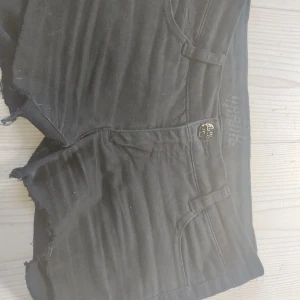 Svarta lågmidjade jeans shorts  - Svarta shorts  med råa kanter och klassisk femficksdesign. De har låg midja och är tillverkade i ett mjukt bomullsmaterial med lite stretch. Perfekta för en chill och avslappnad stil under varma dagar. De står att de är 152 men passar även xs