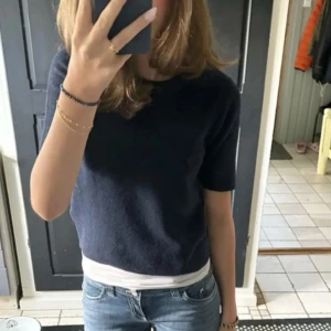 Mörkblå stickad tröja från Nelly - Mysig mörkblå stickad tröja från Nelly med kort ärm och rund halsringning. Helt ny med prislapp kvar 