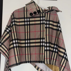  ponchojacka från Burberry - Ponchojacka från Burberry aldrig använd, Perfekt för dig som vill sticka ut med en ikonisk look.står ingen storlek på jackan men skulle säga att den är onesize så den passar alla💗