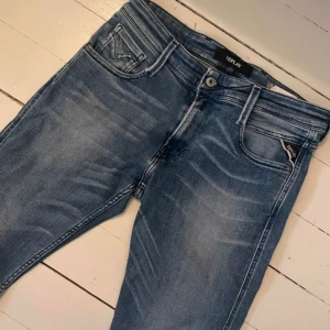 Blå Replay jeans anbass med slim fit - Snygga blå jeans från Replay med klassisk femficksdesign och diskreta slitningar framtill. Jeansen har smal passform och normal midja, perfekta för en avslappnad men trendig look. Materialet är mjukt och stretchigt jeans för extra komfort. 30 34