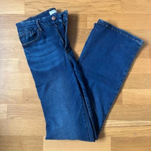 Blå bootcut jeans från Lindex - Snygga blå jeans från Lindex med klassisk bootcut-passform. Jeansen har normal midja, fem fickor och dragkedja med knapp. Tillverkade i mjukt denimtyg som sitter skönt och ger en tidlös look.