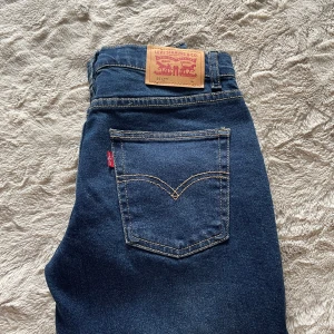 Levi's 551Z blå jeans - Snygga blå Levi's 551Z jeans med klassisk femficksdesign och kontrastsömmar. Jeansen har en rak passform och är tillverkade i slitstarkt denim med den ikoniska läderpatchen bak i midjan. Perfekta för dig som gillar en tidlös och clean look.