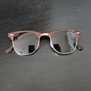 Ray Ban Clubmaster - Snygga solglasögon från Ray-Ban med den klassiska clubmaster designen. De har en brun överdel och guldiga detaljer med mörka glas. Perfekta för en stilren look. Pris är diskuterbart!!! OG fodral medföljer ej!!!