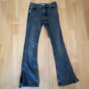 Grå bootcut jeans från Zara - Snygga grå bootcut jeans från Zara med slitsdetalj vid bensluten. Perfekta för en avslappnad stil. Tillverkade i Bangladesh.