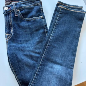 Riktigt snygga Blå jeans från Jacob Cohen i size 26 - Snygga blå jeans från Jacob Cohen med klassisk femficksdesign och kontrastsömmar. Tillverkade av exklusivt japanskt tyg med italienskt hantverk. Pris kan diskuteras. Svarar snabbt. Mått: längd 86 cm och midja 31 cm