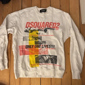 Vit sweatshirt från Dsquared2 - Säljer en cool vit sweatshirt från Dsquared2 med tryck i rött, gult och svart. Tröjan har långa ärmar och en rund halsringning. Perfekt för en avslappnad stil med en touch av attityd. Pris kan förhandlas. Nypris 4100kr