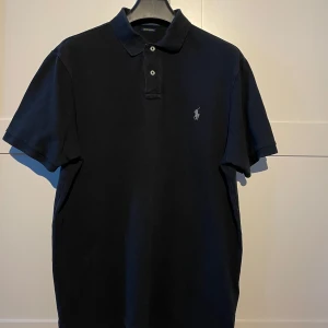 Snygg pike från Ralph Lauren - Stilren Ralph Lauren pike i en klassisk svart färg. Piken är i storlek L. Hör av er vid frågor eller funderingar!