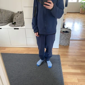 Nike Tech fleece hoodie/byxa mörkblå  - Säljer en mörkblå hoodie med dragkedja samt byxor från Nike. Perfekt för en avslappnad stil. Hoodien och byxan  har en enkel design med diskreta detaljer. Junior XL ( 158-170). 