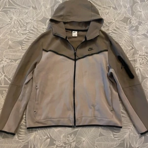 Brun Svart Nike Tech - Den är helt ok använd bra för Att ha till sommar eller höstvibes. Den kan man också köpa till sina nära och kära som ni älskar :) sms 💬 oss om ni vill ha eller köp direkt 