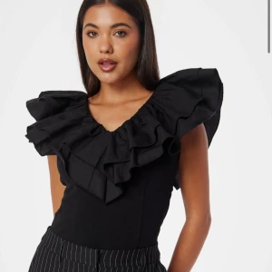 Svart volangtopp - Snygg svart topp med volanger runt halsen och axlarna. Den är använd en gång bara och är från bubbleroom 