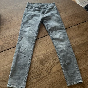 Grå Levis 511 jeans - Snygga grå Levis 511 jeans i en klassisk slim fit passform men jag kan tycka dom är lite pösigare än vanliga slim fit. Perfekta för en stilren look med fem fickor och knappgylf. Tillverkade i slitstarkt denim som håller länge. Storlek 28X32. Använt dom en gång och köptes för 2 månader sen. 
