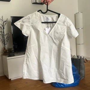 Vit blus med v-ringning - Säljer en stilren vit blus med v-ringning och korta ärmar. 