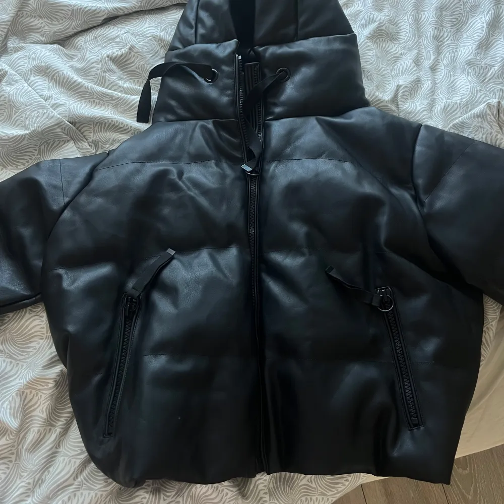 Säljer en svart pufferjacka från Zara med huva och dragkedja. Skinnmaterial. Den är helt ny och oanvänd!!! Pris kan diskuteras! :). Takit.