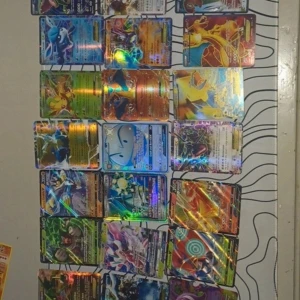 Samling av Pokémon-kort 29 st - En imponerande samling av Pokémon-kort med holografisk effekt. Kort från olika serier och generationer, inklusive populära Pokémon som Charizard och Rayquaza. Perfekt för samlare eller fans av Pokémon-världen. Kortens färger och glans gör dem till ett fantastiskt tillskott till vilken samling som helst.