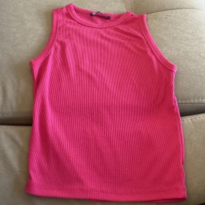 Rosa ribbad linnetopp - Säljer en snygg rosa ribbad linnetopp. Perfekt för varma dagar med sin ärmlösa design. Enkel och stilren, passar till många olika outfits.