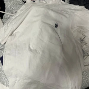 Vit t-shirt från Ralphlauren  - Säljer en klassisk vit t-shirt från Ralphlauren med en liten broderad logga på bröstet. T-shirten är tillverkad i mjuk bomull och har korta ärmar. Perfekt för en avslappnad stil.