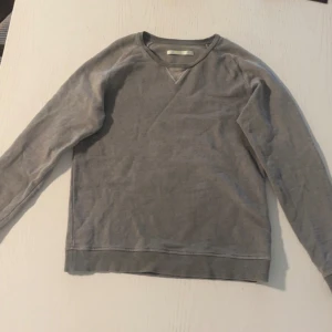 Grå bomullströja från Astrologie Milano - Säljer en stilren grå tröja från Astrologie Milano, tillverkad i Italien. Tröjan är i 100% bomull och har långa ärmar med en klassisk rund halsringning. Perfekt för en avslappnad look.