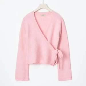 Rosa stickad tröja - Säljer en söt rosa stickad omlottkofta från Gina Tricot. Den har en knytning i sidan och är långärmad. Den är sparsamt använd då jag bara har haft den ett fåtal gånger!☺️