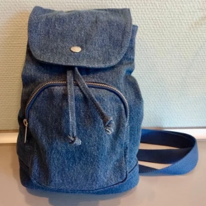 Blå jeansryggsäck från Levi Strauss - Säljer en snygg blå jeansryggsäck från Levi Strauss. Ryggsäcken har en dragkedja framtill och justerbara axelremmar. Perfekt för vardagsbruk med en stilren design och praktisk förvaring.