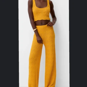 Gul stickad sett - Snygg gul stickad linnetopp och byxor med ett fint mönster. Toppen är croppad och har breda axelband, perfekt för en somrig look. Byxorna är lite baggy och i storlek S medans toppen är i storlek XS. Kan köpas separat, helt ny med lapp på fortfarande. Skriv för bilder 