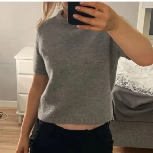 Grå stickad tröja från Zara - Säljer en stilren grå tröja från Zara. Tröjan har en enkel design med korta ärmar och rund hals. Pris kan diskuteras vid snabbt köp. 🩶
