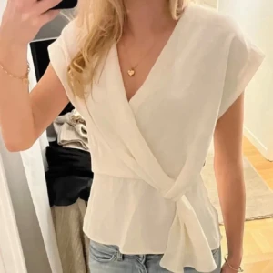 Zara blus  - Snygg vit omlottblus med knytning i midjan. Blusen har en v-ringad design och korta ärmar, vilket ger en stilren och elegant look. Perfekt att matcha med jeans för en avslappnad stil. Har dock lite små fläckar men dom märks inte av ❤️