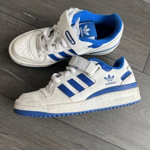 Vita och blå Adidas sneakers - Snygga vita sneakers från Adidas. Modellen forum low, storken 39 1/3💙