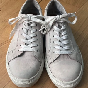 Rosa/beiga sneakers med snörning - Snygga rosa/beiga sneakers med klassisk snörning. Perfekta för en stilren look och passar till det mesta. De har en enkel design med en vit sula och är tillverkade i ett material som ger en skön passform.