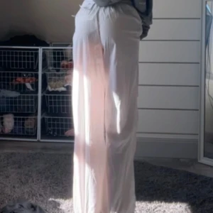 Vita ”parachute” byxor från Bershka - Snygga vita byxor från Bershka med elastisk midja. Byxorna har en loose passform och är perfekta för en avslappnad stil. Tillverkade i ett lätt och bekvämt material. Använt en gång! I helt nytt skick. 