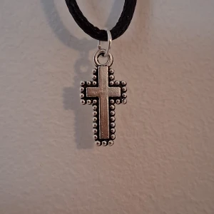 Halsband med korshänge - Snyggt halsband med ett korshänge i silverfärg. Hänget har en dekorativ kant med små kulor som ger det en unik look. Perfekt för att ge en stilren touch till din outfit.