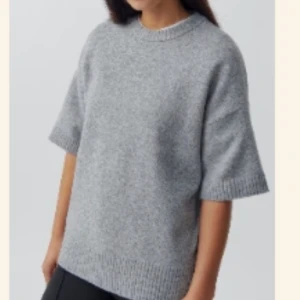 Grå stickad tröja från Gina Tricot  - Säljer en stilren grå stickad tröja från Gina Tricot . Tröjan har en oversized passform och korta ärmar, perfekt för en avslappnad look. Den är tillverkad i ett mjukt material som ger en skön känsla. Passar bra till både jeans och kjol. 🩶 Den är aldrig använd och har även lappen kvar💗