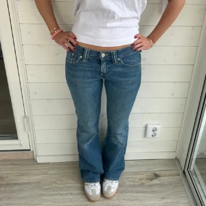 Levis Blå bootcut jeans - Snygga blå bootcut jeans med klassisk femficksdesign och knappgylf. Perfekta för en avslappnad stil. De har en bekväm passform och är tillverkade i jeansmaterial. (Köpta på jeansbolaget här på plick men tyvärr för små)