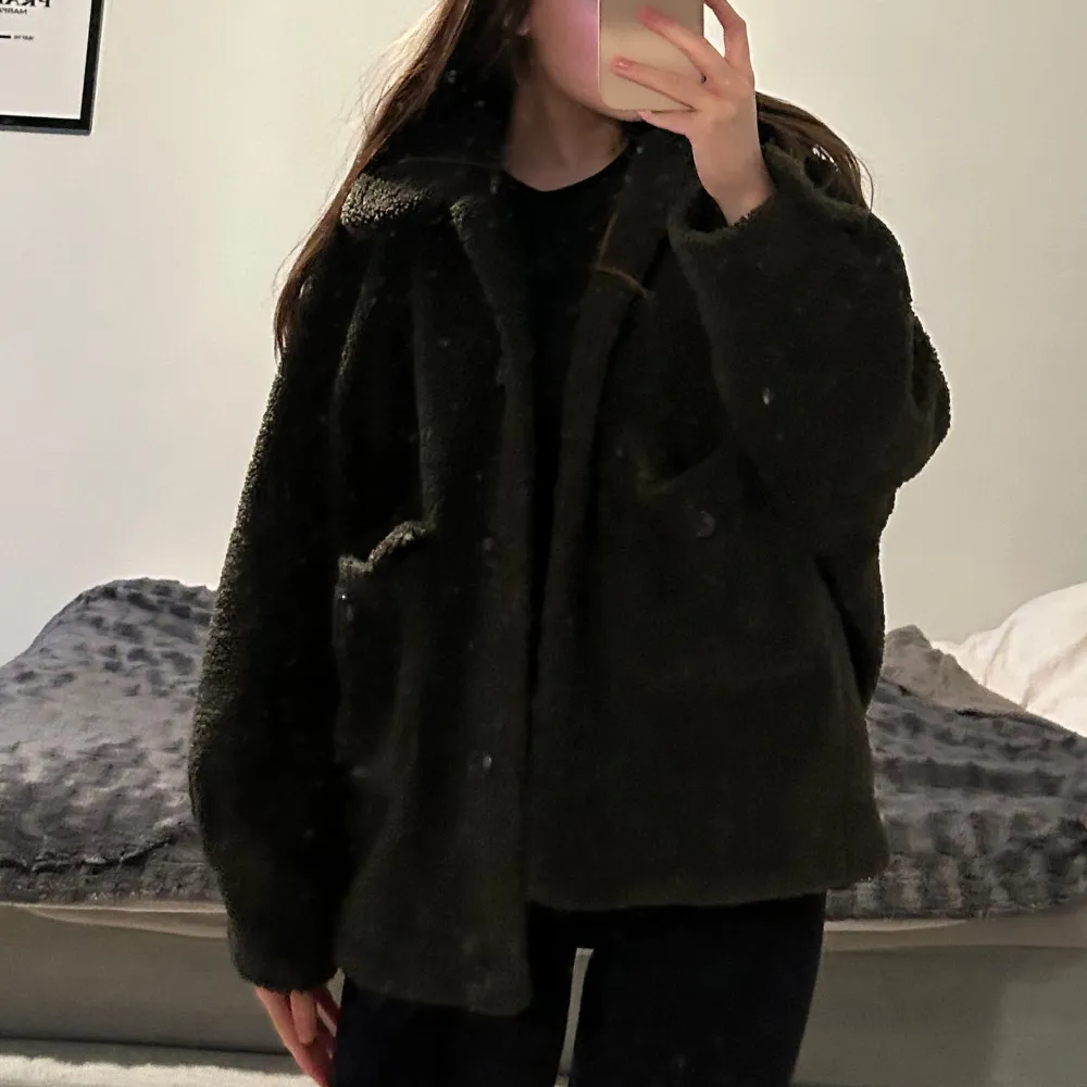 Säljer en mysig mörkgrön teddyjacka med knappar framtill. Jackan har en oversized passform och långa ärmar, perfekt för kyliga dagar. Den är både stilren och bekväm, ett måste i garderoben!. Takit.