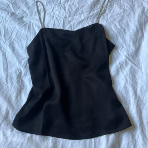 Svart linnetopp från H&M - Svart linnetopp från H&M med tunna glittriga axelband. Endast använd en gång. 