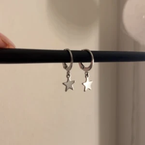 Silverörhängen med stjärnhängen - Snygga silverörhängen med små stjärnhängen. Perfekta för att ge en subtil glans till din stil. De är enkla men eleganta och passar till många olika tillfällen. Aldrig använda 