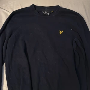 Mörk blå Lyle & Scott tröja - Riktigt snygg Lyle & Scott tröja till ett billigt pris då den har ett litet litet hål. Hålet syns ej så länge man har en mörk tröja under men det är även lätt att laga. ( hemma eller hos skreddare ca100kr)