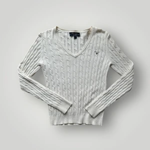 Vit ribbad tröja från GANT - Säljer en stilren vit tröja från GANT i stretchig bomull. Tröjan har ett ribbat mönster och en v-ringad hals. Perfekt för en klassisk och bekväm look. Passar till många olika tillfällen! Mått 📐Längd: 57 cm (halsringens övre kant till nederkant). Bredd: 41 cm (axel till axel).