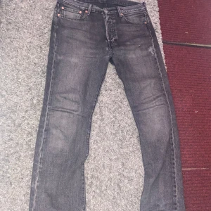 Grå Levis 501 jeans - Snygga grå Levis 501 jeans med klassisk design. De har en rak passform och är perfekta för en avslappnad stil. Jeansen har fem fickor och knappar i gylfen.