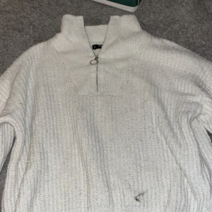 Vit stickad tröja från FB Sister - Säljer en mysig vit stickad tröja från FB Sister. Tröjan har en dragkedja framtill och en hög krage som ger extra värme. Perfekt för kyliga dagar. 🧶