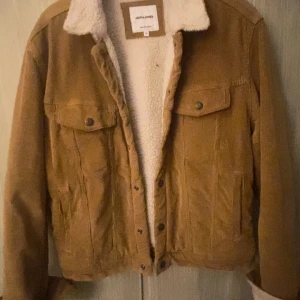 Brun manchesterjacka från Jack &amp; Jones - Säljer en snygg brun manchesterjacka från Jack &amp; Jones med mjukt foder. Jackan har knappar framtill och två bröstfickor med lock. Perfekt för kyligare dagar med sin stilrena design och bekväma passform. Funkar även till våren.