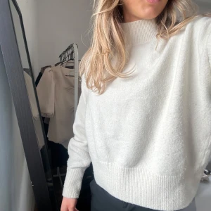 Vit stickad tröja - Säljer en stilren vit stickad tröja med långa ärmar och ribbade muddar. Perfekt för kyligare dagar och enkel att matcha med olika outfits.