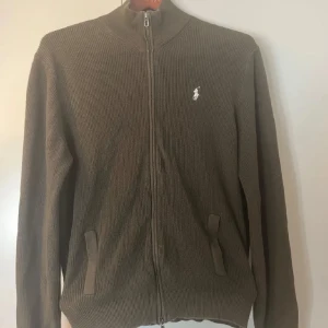 Olivgrön tröja med dragkedja från Ralph Lauren - Säljer en stilren olivgrön tröja från Ralph Lauren, strl L med dragkedja och broderad logga på bröstet. Skick: 8,5/10. Nypris ungefär 2500kr. Skriv om ni har frågor! 