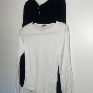 Svart och vit långärmad tröja - Säljer två långärmade tröjor i svart och vit från Gina Tricot med slits i armarna. Perfekta basplagg för garderoben. 🤩Köpta för ungefär 200kr/styck men säljer nu för 170kr för båda!