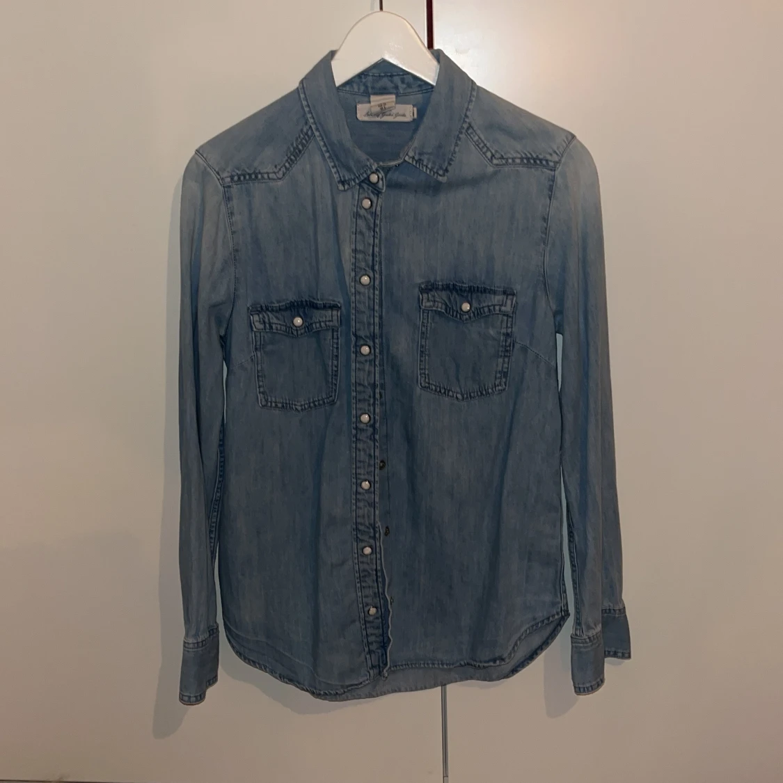 Blå jeansskjorta med knappar